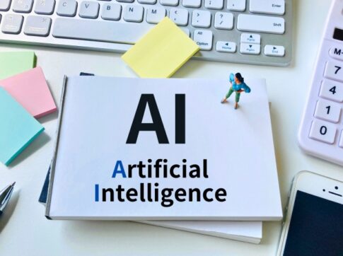 Card on a desk displays 'AI' with 'Artificial Intelligence' text, next to a keyboard and colorful sticky notes.