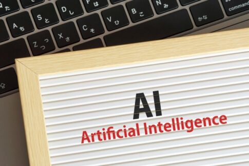 Wooden-framed sign reading 'AI' and 'Artificial Intelligence' on a striped background with a laptop keyboard in the background.