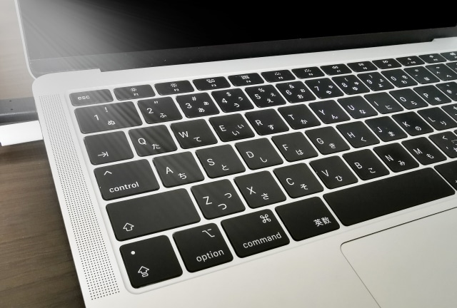 Close-up of a silver laptop keyboard showing black keys with 'control', 'option', and 'command' labels, part of the trackpad area visible below