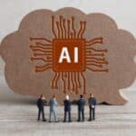 Cloud-shaped cardboard with an orange AI circuit logo and miniature people gathered in front, signaling AI teamwork.