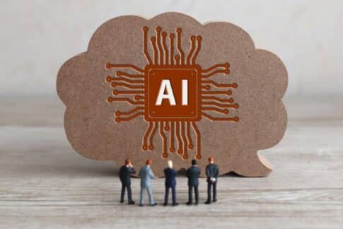 Cloud-shaped cardboard with an orange AI circuit logo and miniature people gathered in front, signaling AI teamwork.