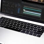 Silver laptop displaying a video editing timeline with multiple tracks on the screen
