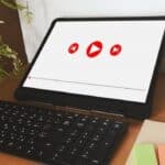 Tablet in landscape on a desk with a keyboard; screen shows three red play icons.