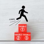 Stick figure jumping over three red blocks labeled TROUBLE 1, 2, and 3