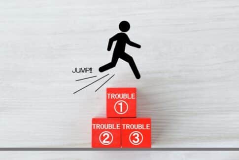 Stick figure jumping over three red blocks labeled TROUBLE 1, 2, and 3
