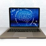 Laptop on a white surface displaying a blue AI brain graphic on the screen.