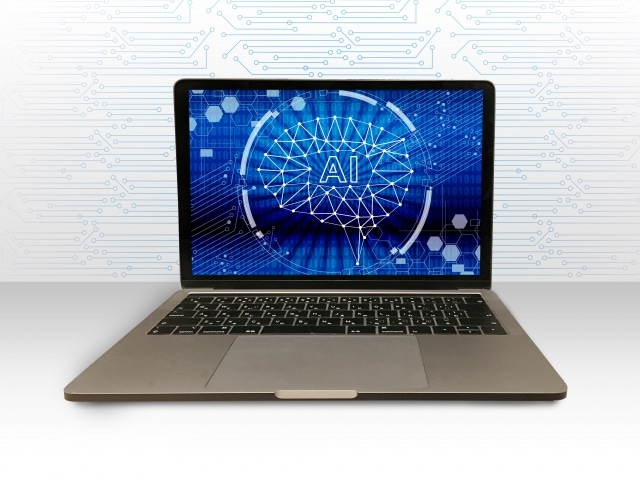 Laptop on a white surface displaying a blue AI brain graphic on the screen.